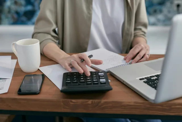 Control de cobros y pagos con calculadora, portátil y anotaciones